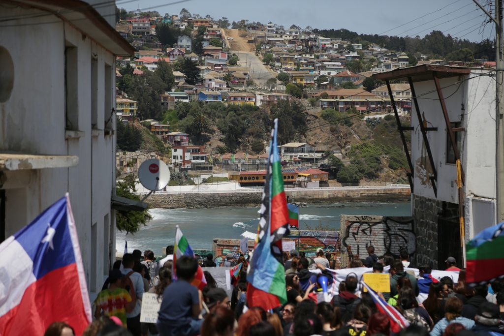 Marcha en Cartagena ocurrida el dia 25 de octubre de 2019. Flamean banderas mapuche y chilena. Al fondo se ve el mar.